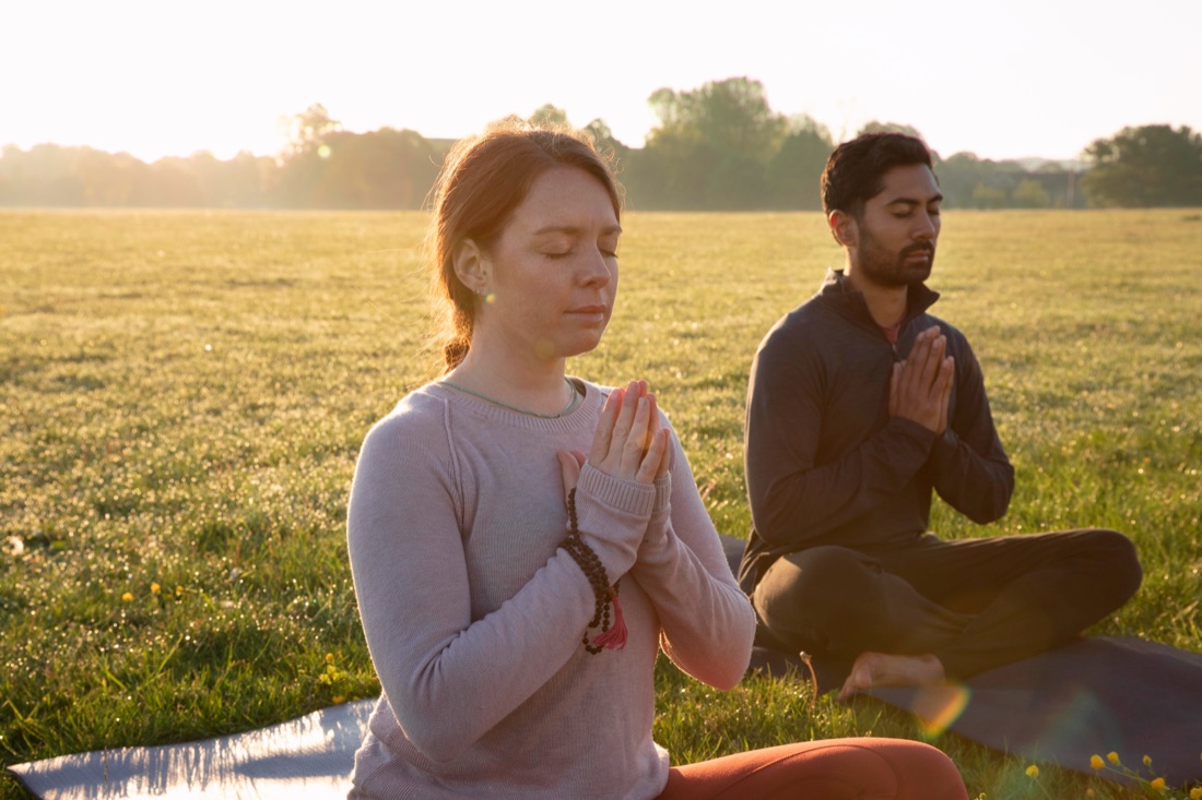Una mujer y un hombre meditando al aire libre